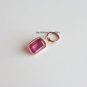 May include: A pink gemstone pendant with a gold bail. The pendant is rectangular in shape and has a smooth, polished finish.  Jay Krishna Jewellers.