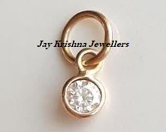 May include: A gold-toned metal charm featuring a single round clear stone set in a bezel, attached to a circular jump ring. The text Jay Krishna Jewellers is printed in black across the center of the charm and the jump ring.