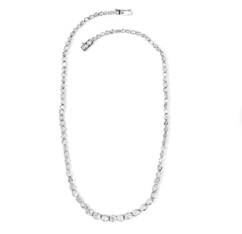 May include: A silver chain necklace with a row of small, round, white diamonds.
