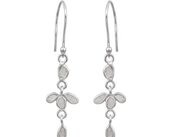 May include: Silver dangle earrings with a cluster of small, clear stones in the shape of a flower. The earrings have a teardrop-shaped stone at the bottom.