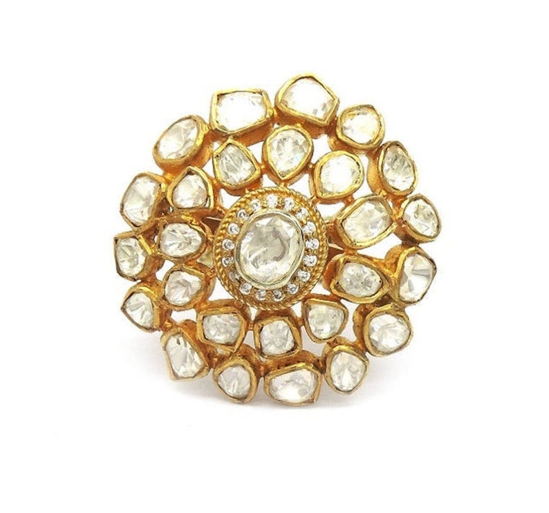 Puede incluir: Un anillo de oro con un gran diamante redondo y claro rodeado de diamantes m&aacute;s peque&ntilde;os en un patr&oacute;n floral.