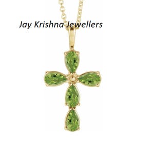 May include: A gold-colored pendant necklace featuring a cross design. The cross is adorned with pear-shaped, light green gemstones. The necklace has a delicate chain and the text "Jay Krishna Jewellers" is visible.