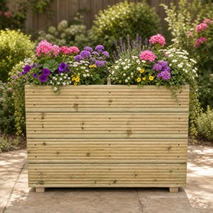 May include: A rectangular wooden planter box constructed from horizontal grooved planks, filled with a vibrant arrangement of pink, purple, white, and yellow flowers, including lavender, petunias, and small daisies, creating a dense floral display.