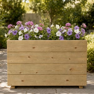 May include: A rectangular wooden planter box constructed from four horizontal light brown planks with visible wood grain and knots. The planter is filled with a dense arrangement of blooming flowers in shades of purple, pink, and white.