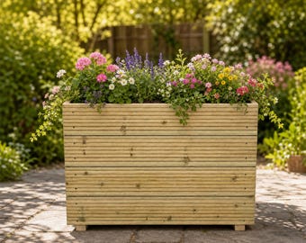 May include: A rectangular wooden planter box constructed from horizontal planks with visible grain and small feet. The planter is filled with a variety of colorful flowers including pink geraniums, purple salvia, white daisies, and small yellow blossoms.