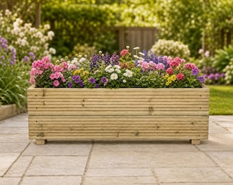 May include: A rectangular wooden planter box with horizontal grooved slats, filled with a vibrant assortment of blooming flowers in shades of pink, purple, white, and yellow, supported by small block feet on a stone patio surface.