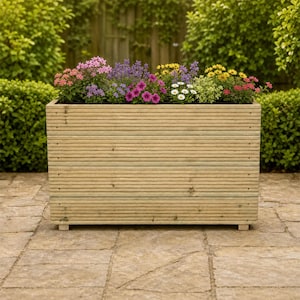 May include: A rectangular wooden planter box constructed from horizontal grooved planks, featuring a natural light brown finish and small feet, filled with a vibrant assortment of pink, purple, white, and yellow flowers in full bloom.