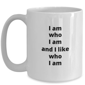 Puede incluir: Taza de cer&aacute;mica blanca con asa curva. La taza presenta el texto "I am who I am and I like who I am" en negro, alineado verticalmente en el lateral. La taza est&aacute; dise&ntilde;ada para bebidas calientes.