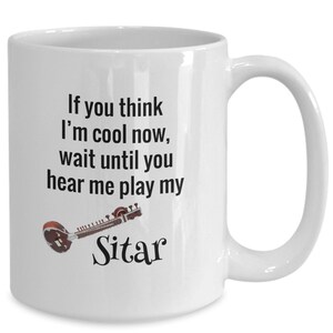 May include: White ceramic mug with a black text that reads "If you think I'm cool now, wait until you hear me play my Sitar." A brown and red sitar graphic is also on the mug.