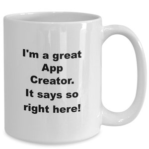 May include: White ceramic mug with a curved handle. The mug has black text that reads, "I'm a great App Creator. It says so right here!" The mug is designed for hot beverages.