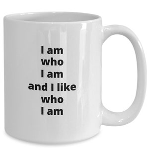 Puede incluir: Taza de cer&aacute;mica blanca con asa curvada. La taza presenta el texto "I am who I am and I like who I am" en negro, alineado verticalmente. La taza est&aacute; dise&ntilde;ada para bebidas calientes.