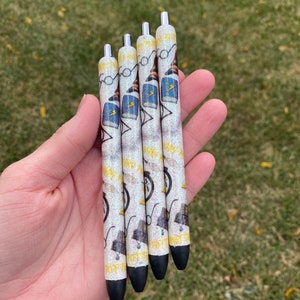 May include: Four black and white pens with a glitter finish. The pens have a Harry Potter theme with images of a book, glasses, a hat, and a lightning bolt.