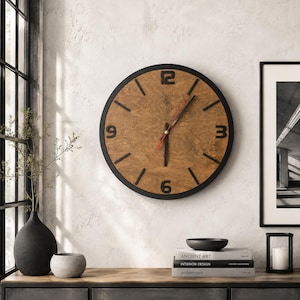 Könnte beinhalten: Eine runde Wanduhr mit schwarzem Rahmen und einem Zifferblatt aus braunem Maserholz. Die Uhr verfügt über schwarze Ziffern an den Positionen 3, 6, 9 und 12 Uhr, schwarze Stunden- und Minutenzeiger sowie einen dünnen roten Sekundenzeiger.