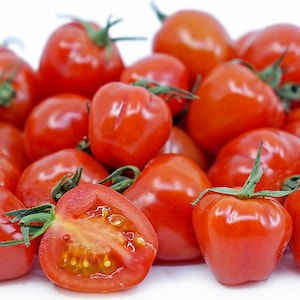 May include: A close-up of a pile of small, red, cherry tomatoes. The tomatoes are arranged in a random pattern and some are cut in half, revealing the seeds inside.