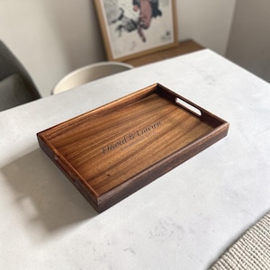 May include: A rectangular wooden serving tray with a dark brown finish and integrated side handles. The centre of the tray features the engraved text David & Lauren Established 2016 in a script and sans-serif font combination.