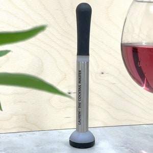 May include: A silver cocktail muddler with a black rubber top and a personalised inscription that reads "Lauren - The Cocktail Master".
