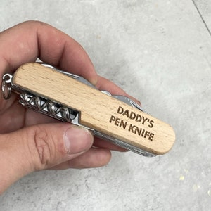 May include: A multi-tool pocket knife with a wooden handle, a silver blade and the words "Daddy's Pen Knife" engraved on the handle.