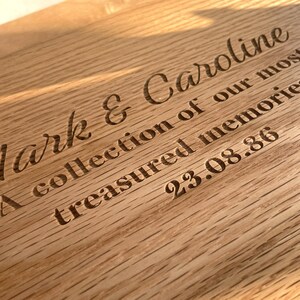 Pode incluir: Close-up de uma placa de madeira com texto gravado. O texto diz "Mark & Caroline, A collection of our most treasured memories, 23.08.86". A madeira tem um gr&atilde;o natural e uma cor castanha clara e quente.