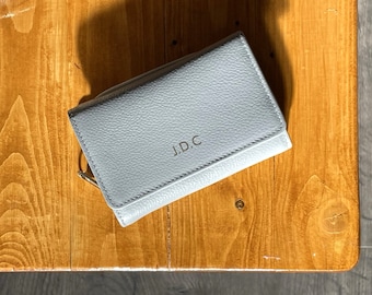 以下が含まれることがあります： 前面に「J.D.C.」の刻印が施された、金色のジッパーが付いた灰色の革財布です。