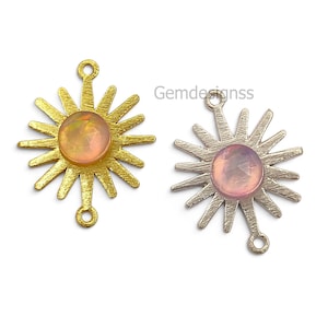 Puede incluir: Dos conectores de joyería en forma de sol con rayos texturizados. Uno es de tono dorado con una piedra redonda translúcida color melocotón, y el otro es de tono plateado con una piedra redonda translúcida rosa. Ambos tienen pequeñas anillas arriba y abajo.