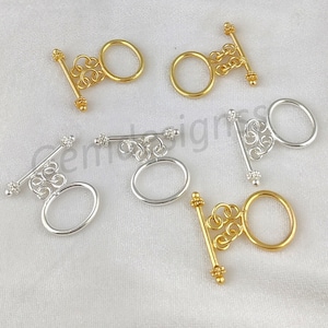 Puede incluir: Seis cierres de palanca de plata y oro con diseños ornamentados. Los cierres son de metal y tienen un acabado pulido. Son perfectos para agregar un toque de elegancia a las joyas u otras artesanías.