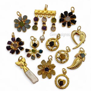 Könnte beinhalten: Eine Sammlung goldfarbener Anhänger mit verschiedenen Edelstein- und Perlenakzenten. Designs umfassen Blumen-, Stern-, Herz- und Blattformen. Einige Anhänger weisen farbige Edelsteine auf, andere eine einzelne Perle oder eine Ansammlung von Steinen.