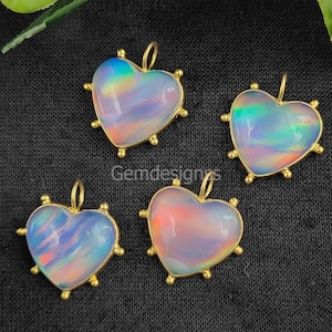 May include: Four iridescent heart-shaped pendants with gold settings. The pendants have a rainbow effect and are set in a gold frame with small gold beads around the edges.