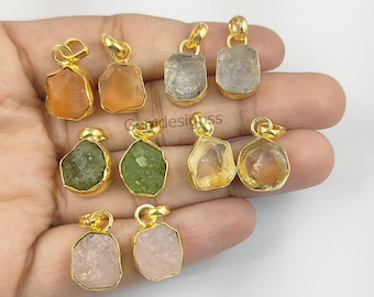 Può includere: Assortimento di otto ciondoli in pietra preziosa placcati in oro. I ciondoli presentano vari colori e forme, tra cui arancione, verde, giallo e rosa. Ogni ciondolo ha una ghiera in oro per essere attaccato a una catena o un cordoncino.