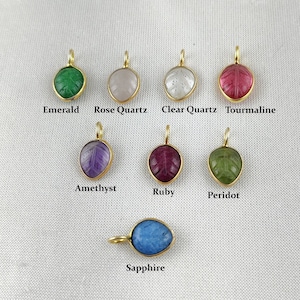 Può includere: Nove ciondoli in oro con diverse pietre preziose colorate, ognuno con un design a foglia scolpita. Le pietre preziose sono smeraldo, quarzo rosa, quarzo trasparente, tormalina, ametista, rubino, peridoto e zaffiro.