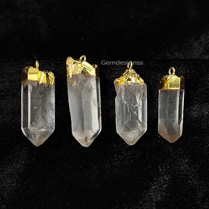 May include: Four clear quartz crystal pendants with gold-plated tops. The pendants are different sizes and shapes.