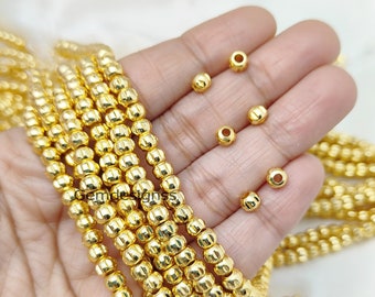 Pode incluir: Um fio de contas de metal dourado com uma superfície texturizada. As contas são redondas e têm um design ligeiramente elevado. As contas são enfiadas em um fio transparente e têm um diâmetro de aproximadamente 6 mm.
