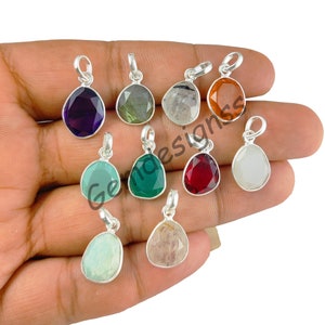 May include: Assortment of ten silver pendant charms with various gemstone cabochons. The gemstones include amethyst, labradorite, clear quartz, carnelian, green chalcedony, ruby, white agate, and aquamarine.