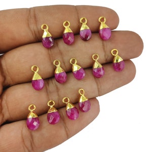 Op de afbeelding: Een verzameling van 12 roze edelsteen-traanhangers met vergulde accenten. De hangers zijn gefacetteerd en hebben een traanvorm. Ze zijn perfect voor het maken van sieraden.