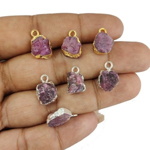 Puede incluir: Siete colgantes de piedra de rubí rosa con engastes de oro y plata. Los colgantes tienen una forma irregular y un aspecto tosco y natural.