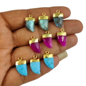 May include: A set of eight gold-plated gemstone pendants in the shape of a fang. The pendants are made of labradorite, chalcedony, and turquoise.