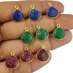 以下が含まれることがあります： 花が彫刻されたデザインの金メッキペンダントチャーム9個。チャームは3個が青、3個が緑、3個が赤です。