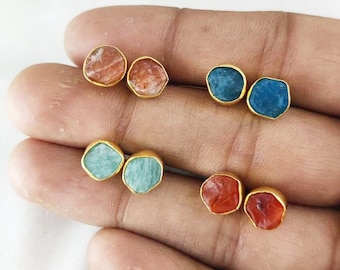 Puede incluir: Seis pares de pendientes chapados en oro con piedras preciosas de diferentes colores. Los pendientes presentan una variedad de colores, incluyendo rojo, naranja, azul y verde.