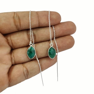 Może przedstawiać: Srebrne kolczyki typu threader z markizowymi, szmaragdowozielonymi kamieniami szlachetnymi. Kolczyki posiadają delikatny łańcuszek i długi, cienki sztyft, który przewleka się przez ucho. Kamienie osadzone są w srebrnej oprawie.