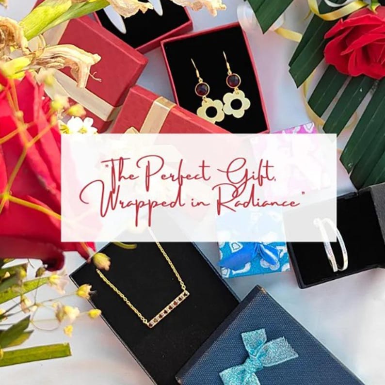 May include: Overhead view of jewellery gift boxes in red, black, and blue. The boxes contain gold earrings, a gold necklace, and a silver bracelet. The image text reads: "The Perfect Gift, Wrapped in Radiance."