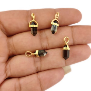 May include: Four gold-plated gemstone pendants with a pointed, crystal-like shape. The gemstones are a dark brown colour.