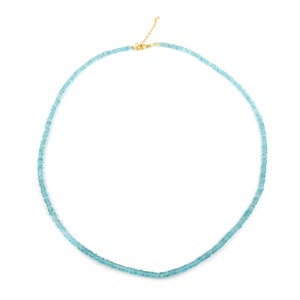 May include: A delicate necklace featuring small, light blue beads. The beads are strung together to form a double strand. The necklace has a gold-colored clasp and chain. The jewelry is displayed against a white background.