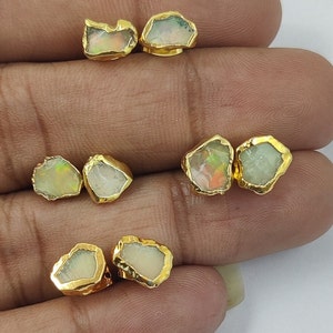 Puede incluir: Un par de pendientes de oro con piedras preciosas de ópalo. Los pendientes tienen la forma de piedras irregulares talladas en bruto.