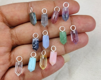May include: A collection of 13 gemstone pendants in various colors, including clear, pink, green, blue, and purple. Each pendant is shaped like a pointed crystal and has a silver bail.