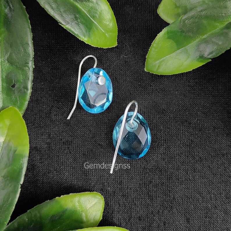 May include: A pair of silver dangle earrings with light blue faceted gemstone drops.