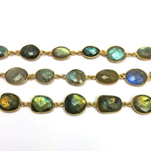 May include: A strand of gold chain with oval-shaped labradorite gemstones. The stones are a mix of green, blue, and gold.