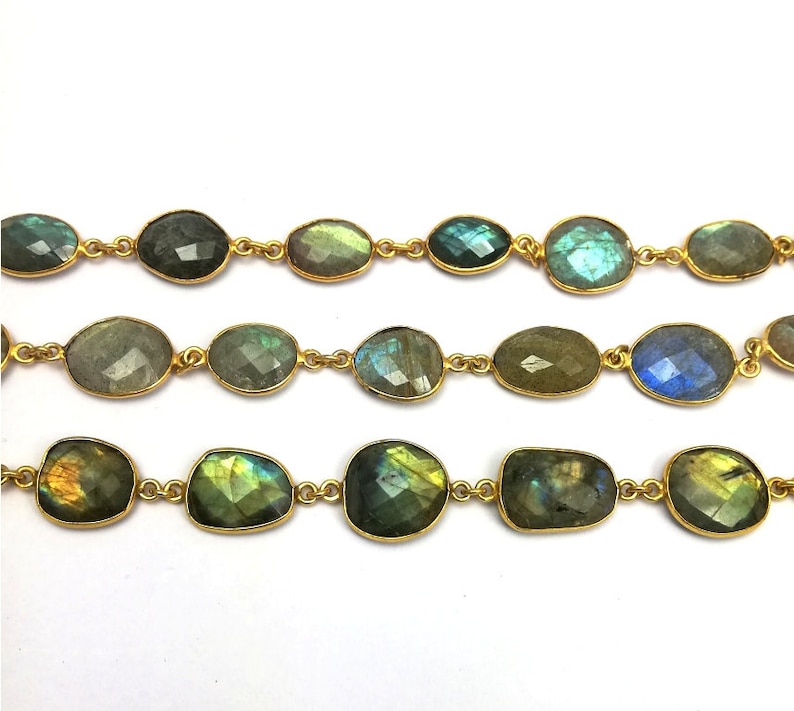 May include: A strand of gold chain with oval-shaped labradorite gemstones. The stones are a mix of green, blue, and gold.