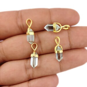 May include: Four gold-plated crystal point pendants. Each pendant features a clear quartz crystal point with a gold-plated wire wrap and a gold-plated bail.