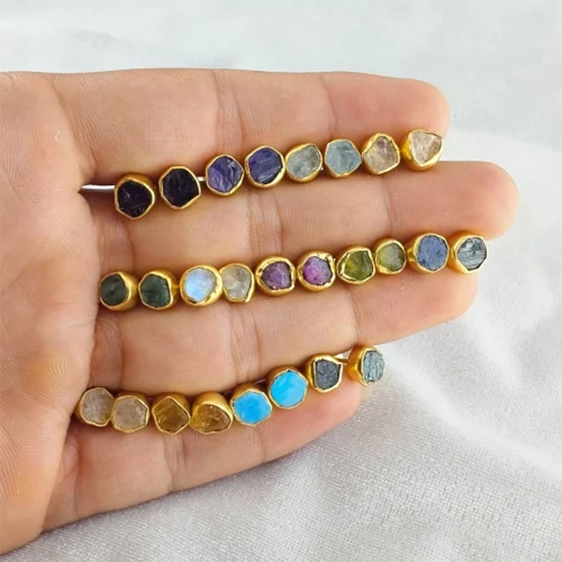Puede incluir: Surtido de 18 pendientes chapados en oro con varias piedras semipreciosas, incluyendo amatista, aguamarina, turquesa y esmeralda.