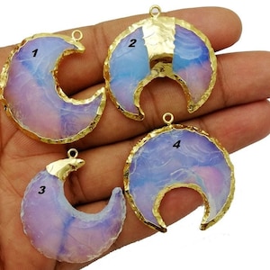 May include: Four crescent moon pendants with a gold-coloured trim and a loop for hanging. The pendants have a translucent, opalescent appearance with shades of lavender, blue, and white. Each pendant is numbered 1 through 4.