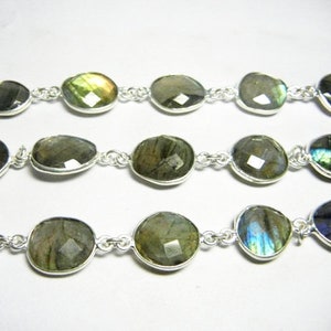 May include: A silver chain necklace with oval-shaped labradorite gemstones. The stones have a iridescent sheen with shades of green, blue, and gold.